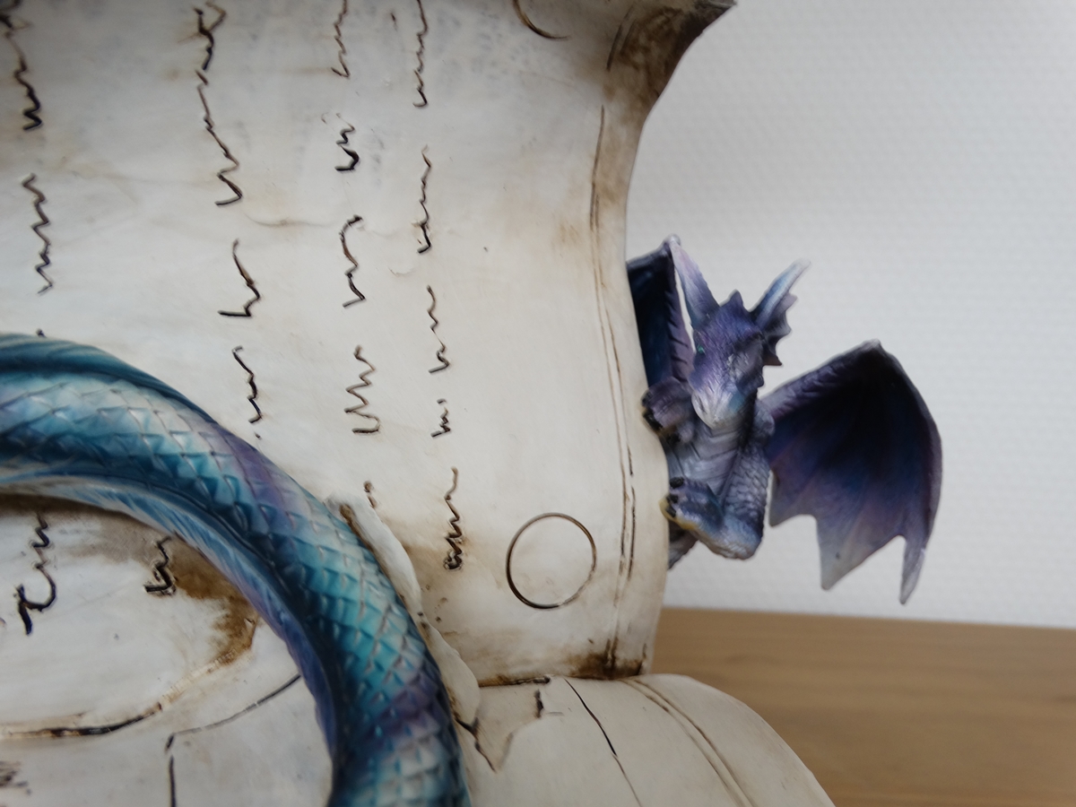 Blue dragon on book, with small purple dragon