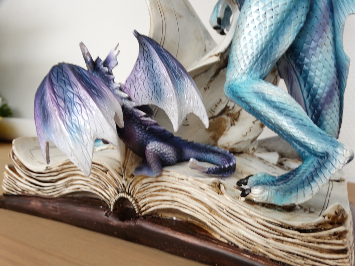 Blue dragon on book, with small purple dragon